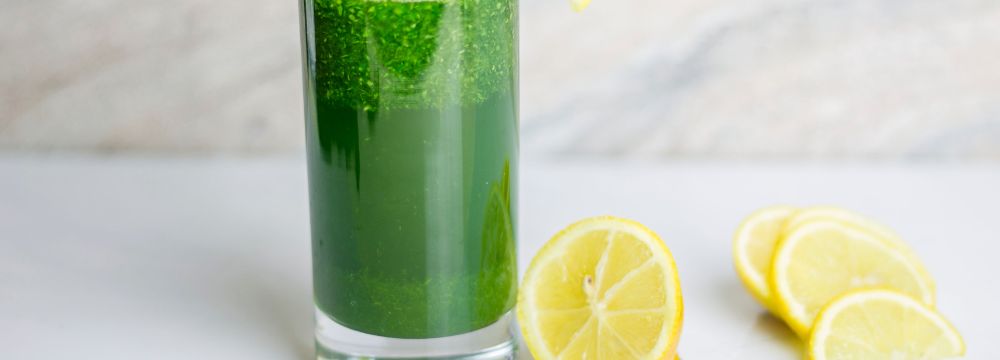 Green juice drink in glass with lemons