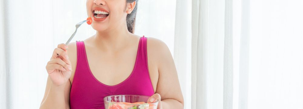 Woman eating bowl of salad after bariatric surgery 
