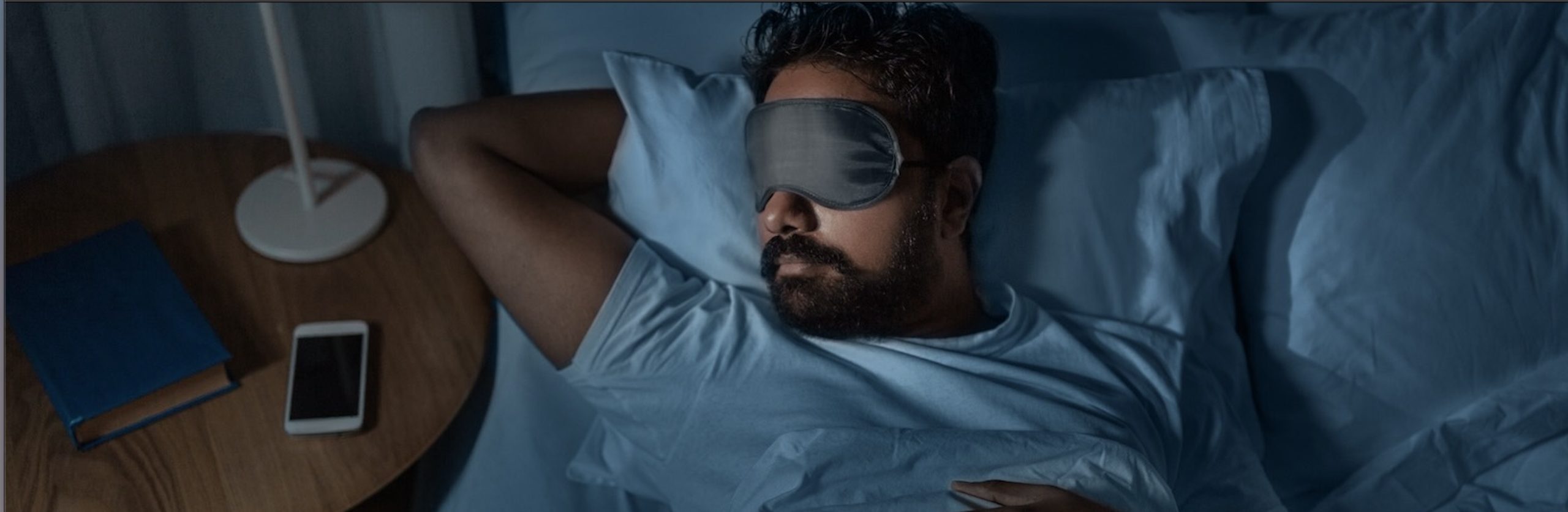 Man lying in bed sleeping with eye mask on face 