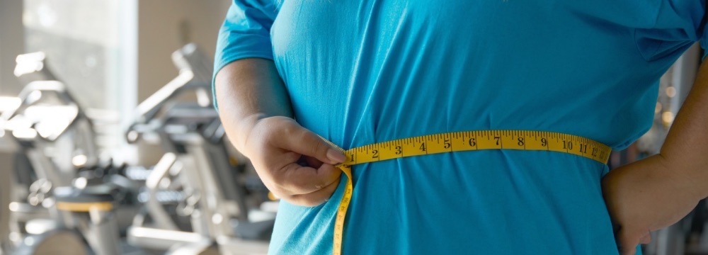 Woman measuring waist with measuring tape, in gym