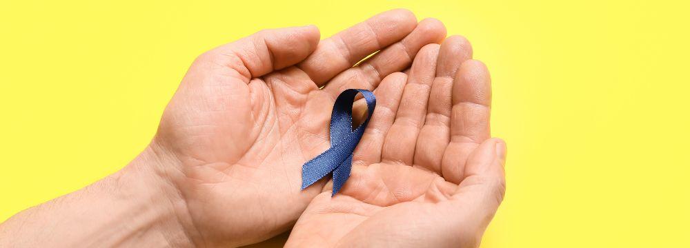 Colorectal cancer survivor holds blue ribbon celebrating new research toward cure for cancer 