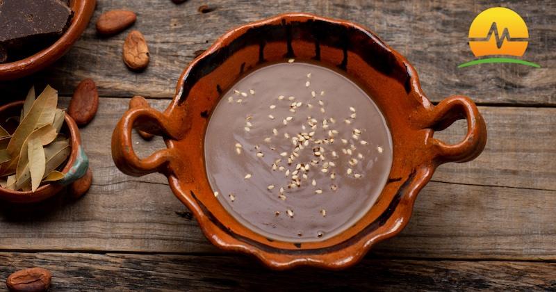 Homemade mole sauce in an orange and brown ceramic bowl on wooden table. MASJax logo in top right corner.