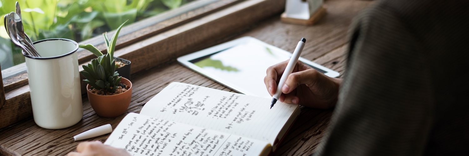 Woman writing in journal by window