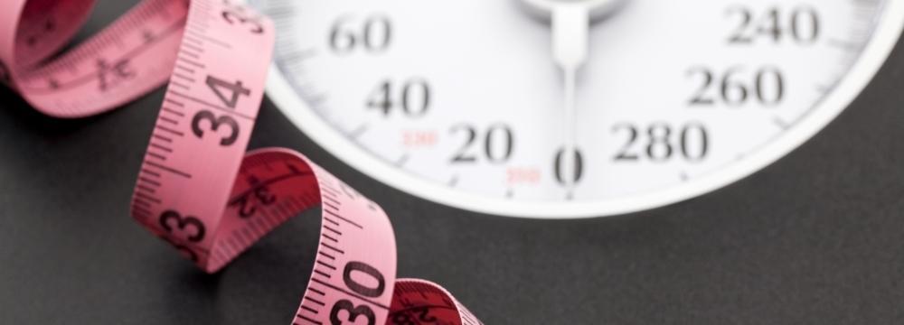 Pink measuring tape coiled onto of a scale