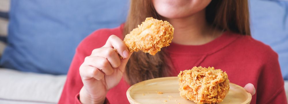 Woman eating fried chicken on plate