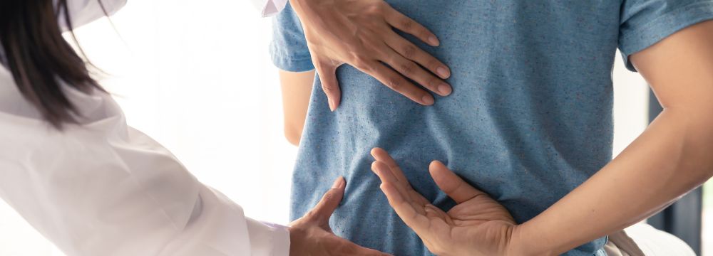 Man holding back while doctor touches it with both hands